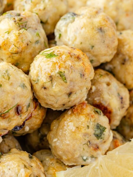 Close up of the cooked meatballs with greek flavors and a lemon wedge.