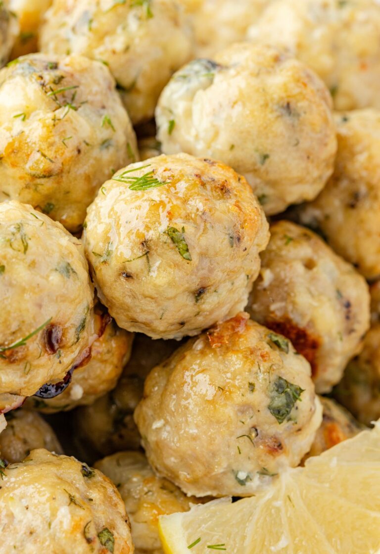 Close up of the cooked meatballs with greek flavors and a lemon wedge.