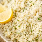 Serving bowl of greek rice with a lemon wedge.
