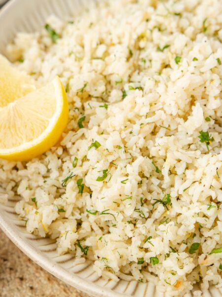 Serving bowl of greek rice with a lemon wedge.