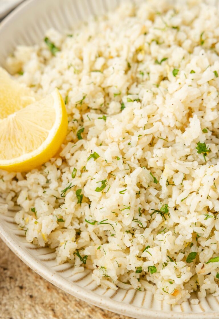 Serving bowl of greek rice with a lemon wedge.