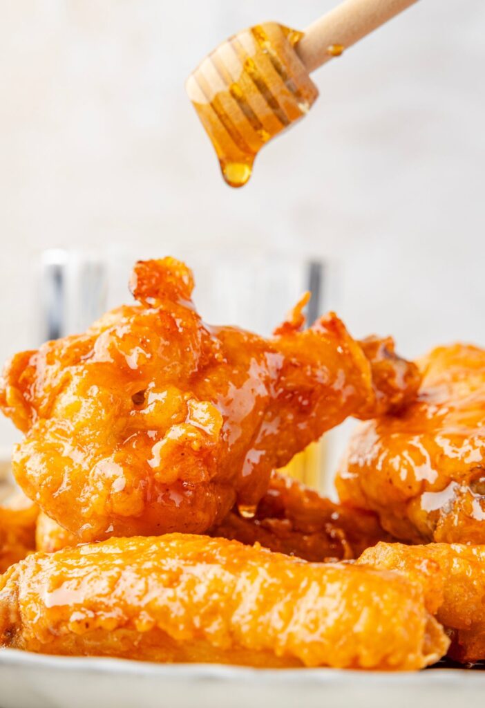 Chicken wings with honey being drizzled over top