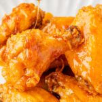 Honey being drizzled over top the chicken wings