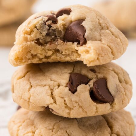 A stack of three eggless chocolate chip cookies with chocolate chips.