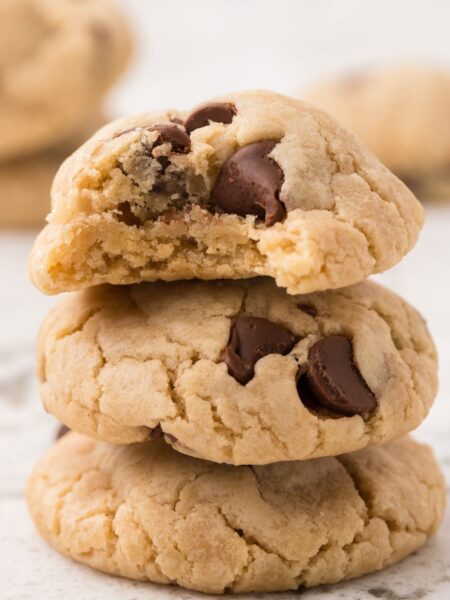 A stack of three eggless chocolate chip cookies with chocolate chips.