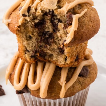 Stack of two muffins with chocolate chips and a peanut butter glaze on top.