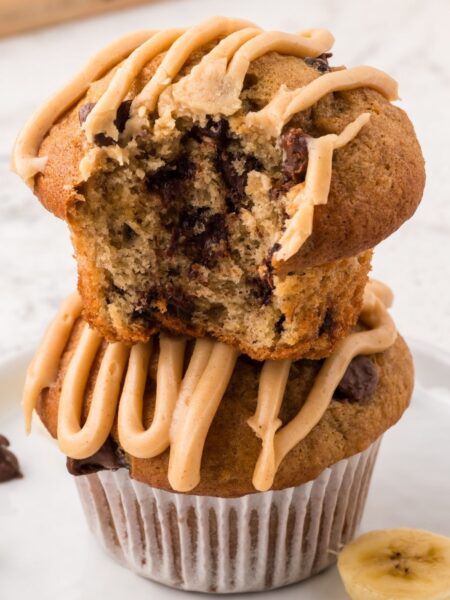 Stack of two muffins with chocolate chips and a peanut butter glaze on top.