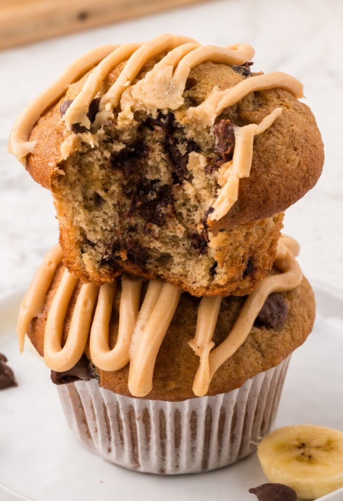 Stack of two muffins with chocolate chips and a peanut butter glaze on top.