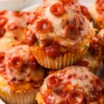 Pile of pizza muffins on a white plate with pepperoni.