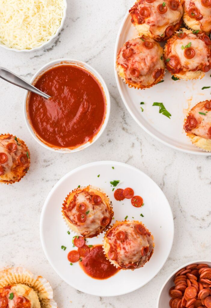 Top view of the muffin pan with a pizza muffin on a serving plate.