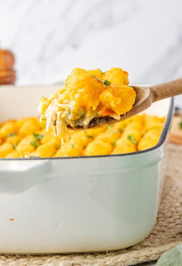 Spoon with some casserole on it above the casserole dish
