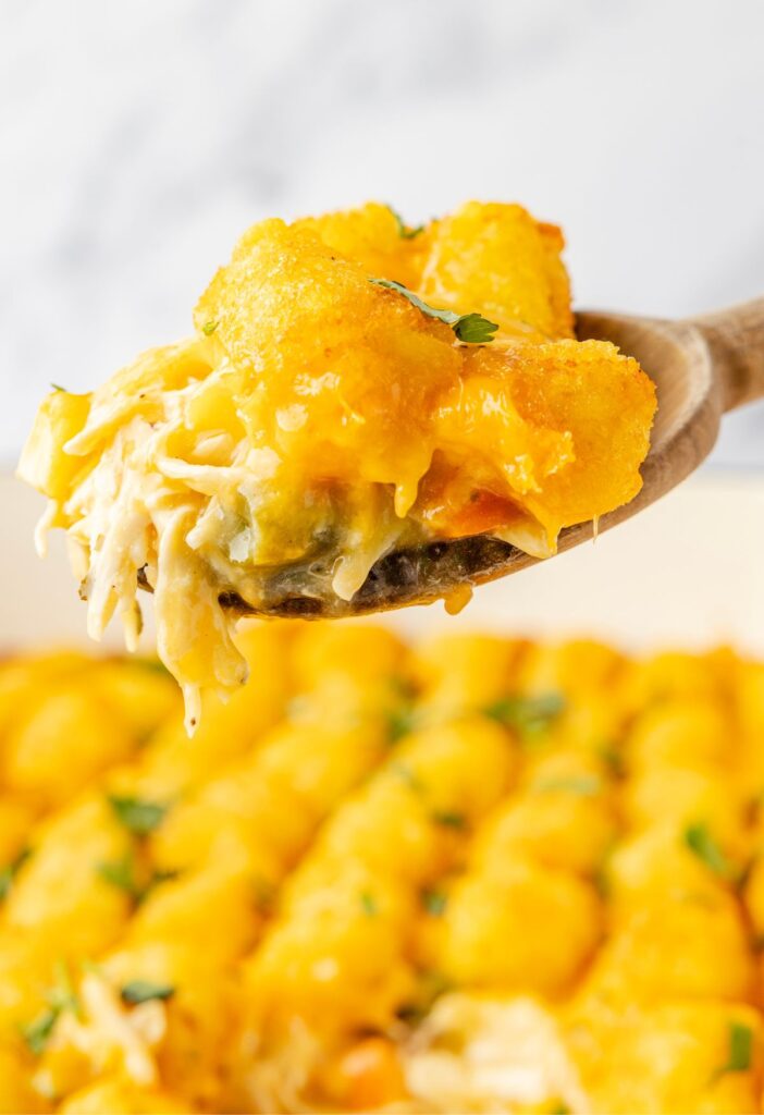 A wooden spoon with a serving of the chicken casserole on it.