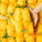 Tater tot casserole with a wooden spoon in it.