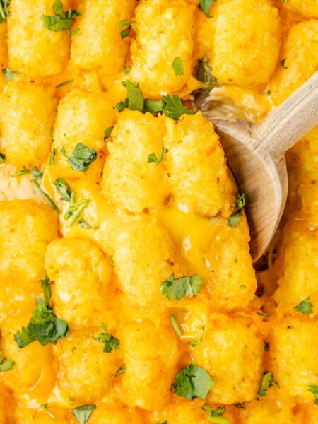 Tater tot casserole with a wooden spoon in it.