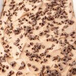 A cake with chocolate whipped cream frosting and chocolate curls on top.