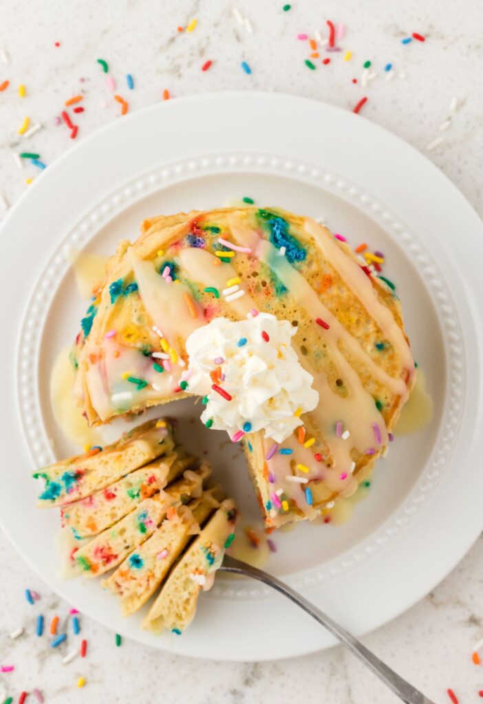 Top view of stack of pancakes with a fork with some pancake on it to show the fluffy pancake.