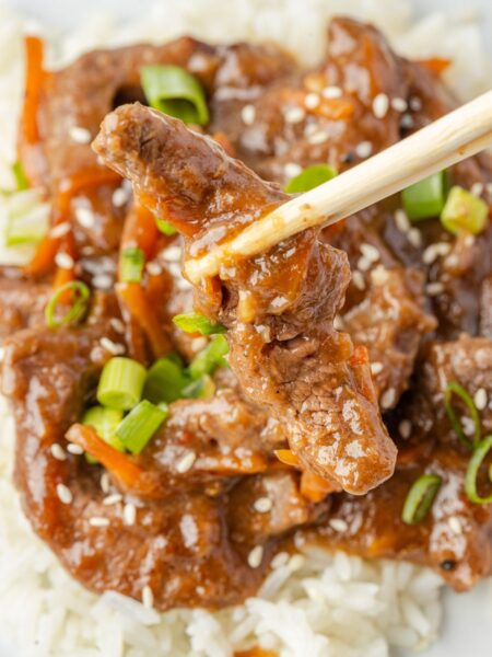 Chopsticks holding a piece of the beef