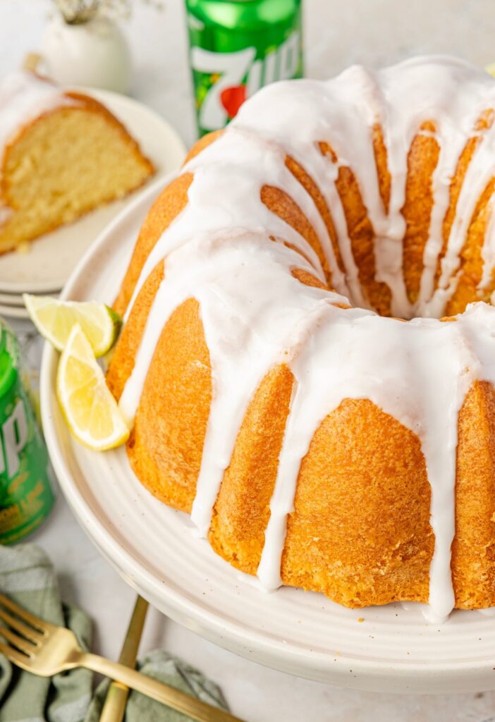 7up cake on a cake stand with a piece of it on a plate beside it.