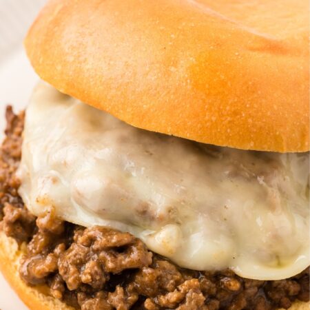 A sloppy Joe with ground beef filling and sliced cheese.