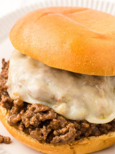A sloppy Joe with ground beef filling and sliced cheese.