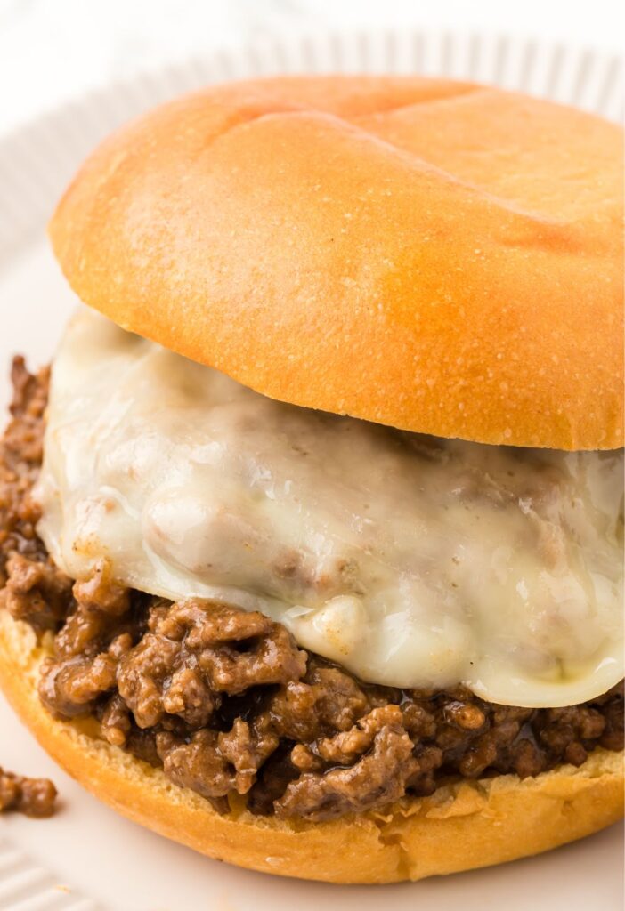 A sloppy Joe with ground beef filling and sliced cheese.