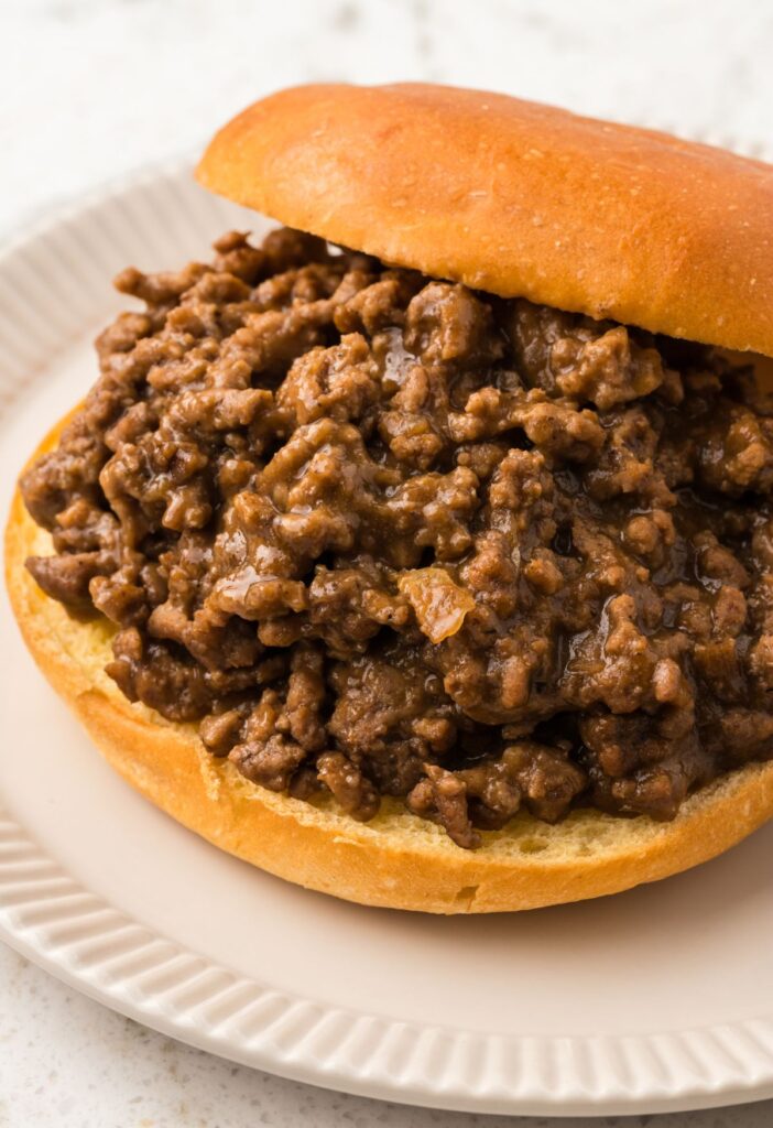 A sloppy Joe in a bun on a white plate