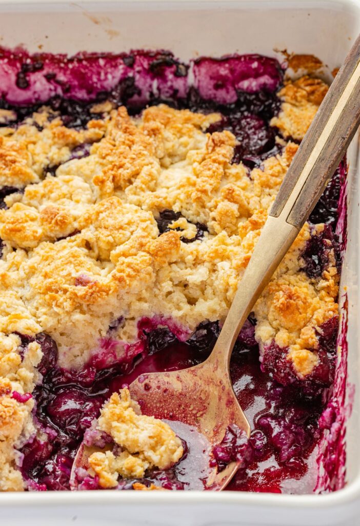 A pan of the blueberry crumble with the serving spoon inside of it