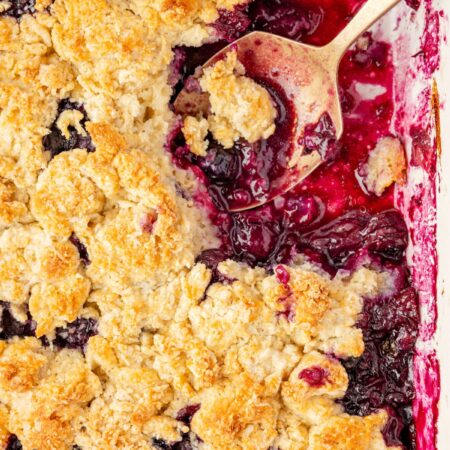 A top view of the blueberry crumble inside the baking pan with a serving spoon.