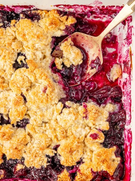 A top view of the blueberry crumble inside the baking pan with a serving spoon.