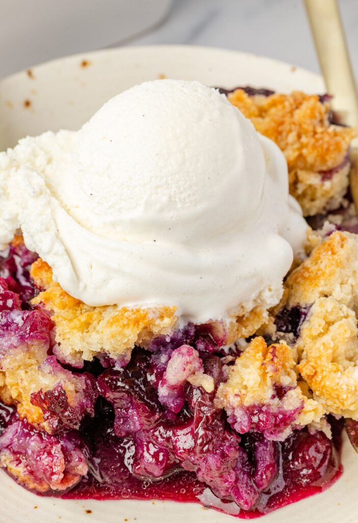 A serving of the blueberry dessert topped with ice cream.