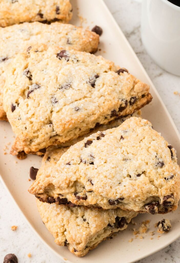 Baked ready to serve chocolate chip scones on a white platter.