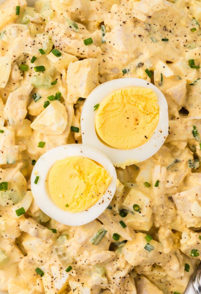 Close up image of the chicken salad with a deviled egg on top of it.