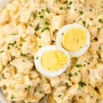 Chicken salad with deviled eggs inside a bowl with a serving spoon.