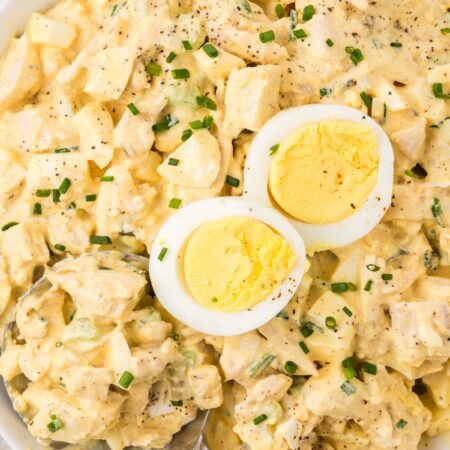 Chicken salad with deviled eggs inside a bowl with a serving spoon.
