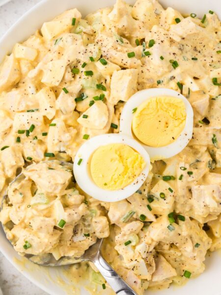 Chicken salad with deviled eggs inside a bowl with a serving spoon.