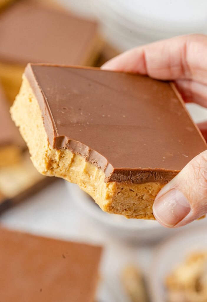 A hand holding one of the no bake peanut butter bars