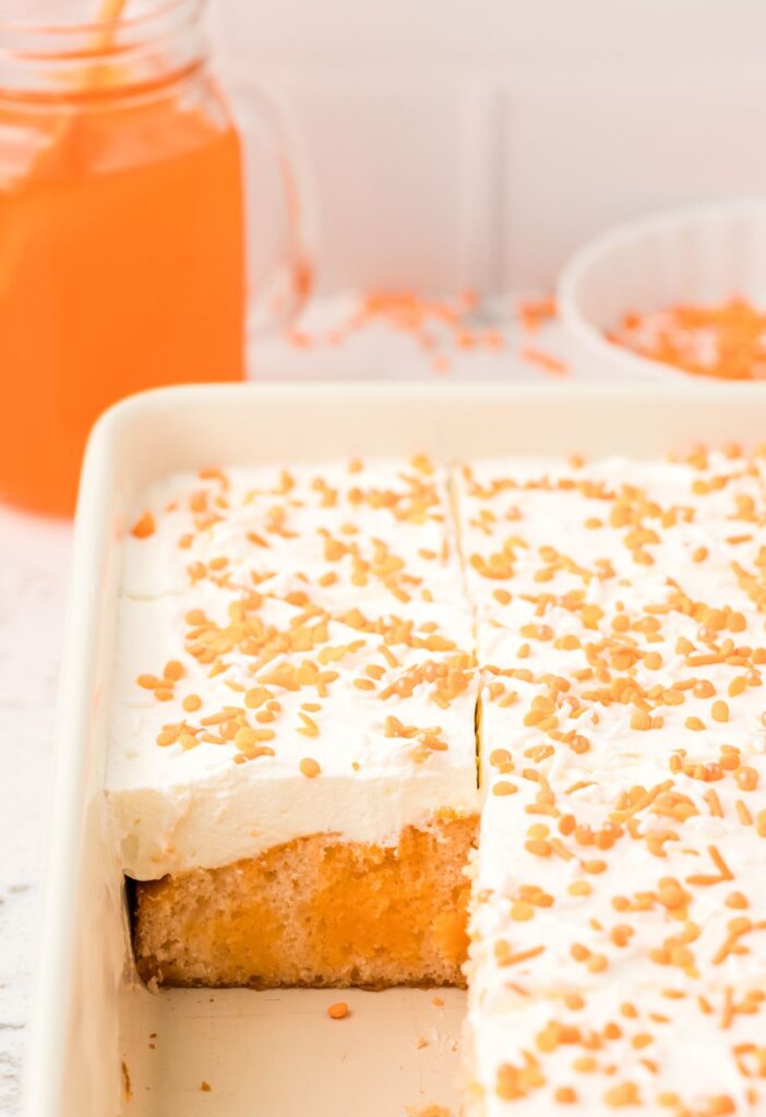 Cake pan of poke cake with orange crush soda in a cup.