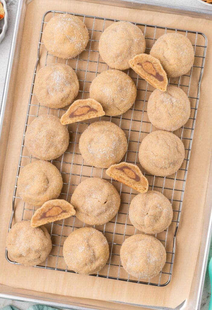 Baked cookies on a cooling rack with some cut half.