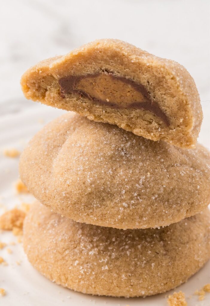 Stack of cookies with the top open so you can see the Reese's on the inside.