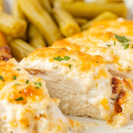 A side view of a plate with ranch chicken on it, cut into slices, to see the juicy center of the chicken.