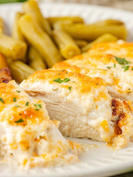 A side view of a plate with ranch chicken on it, cut into slices, to see the juicy center of the chicken.