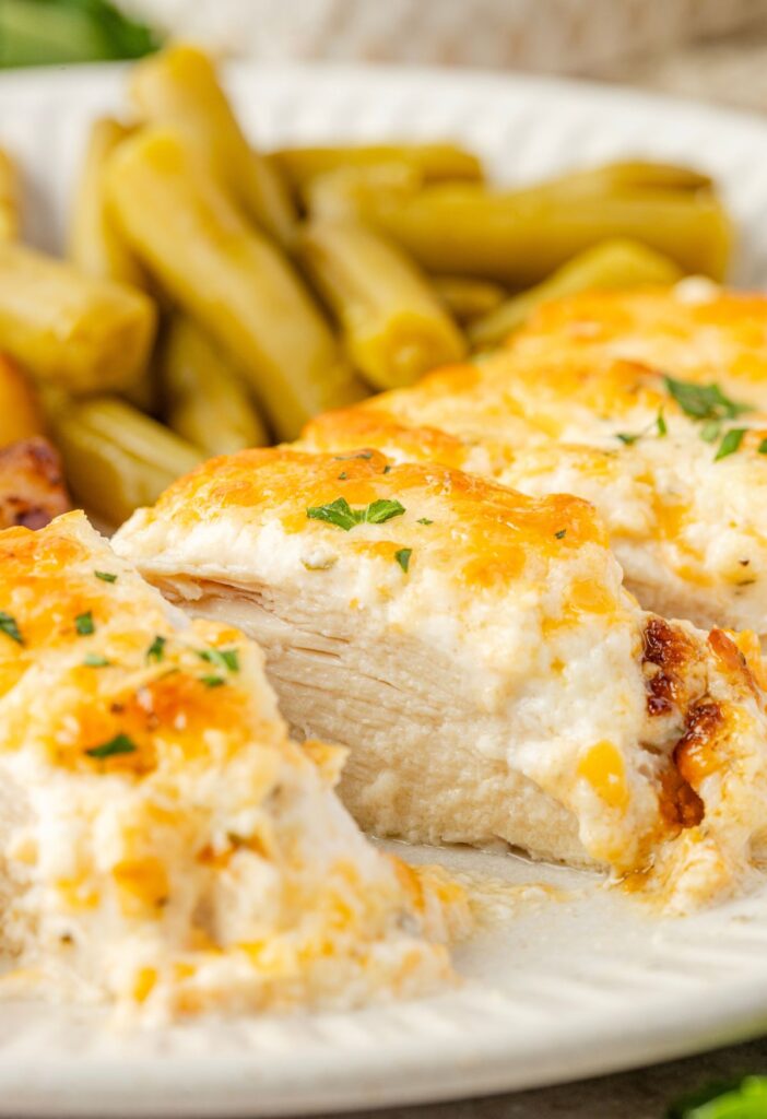 A side view of a plate with ranch chicken on it, cut into slices, to see the juicy center of the chicken.