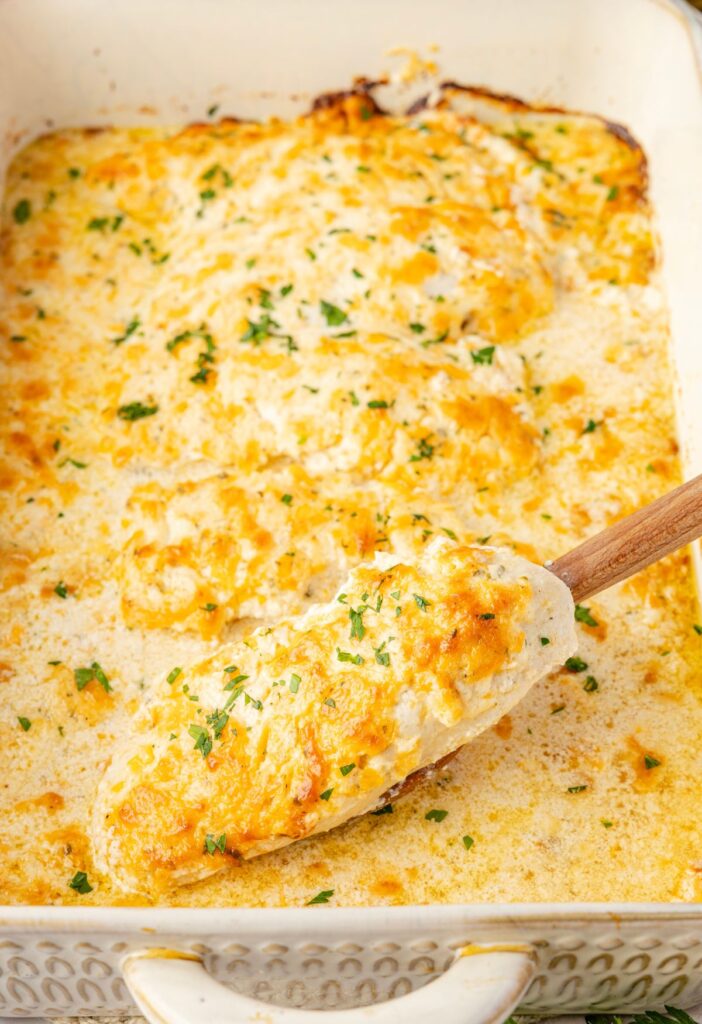 The baking dish of the chicken with a serving spatula in it.