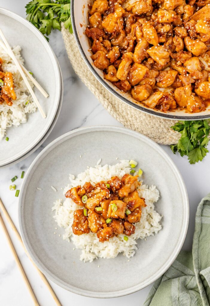 Top view of the skillet pan of chicken thighs in sweet chili sauce and a serving of it over white rice.