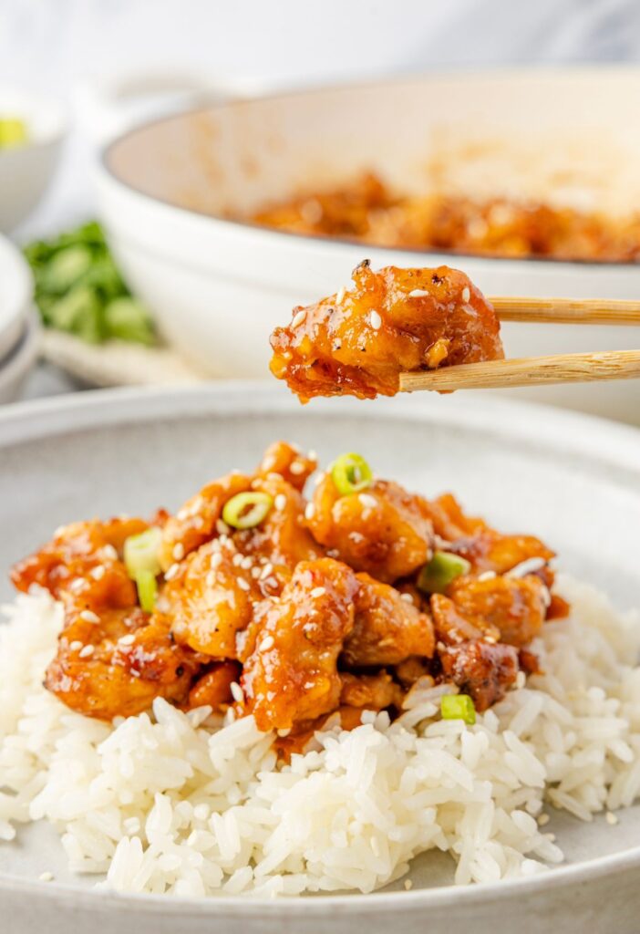 A serving of the chicken thighs with a chopstick with a piece in it.