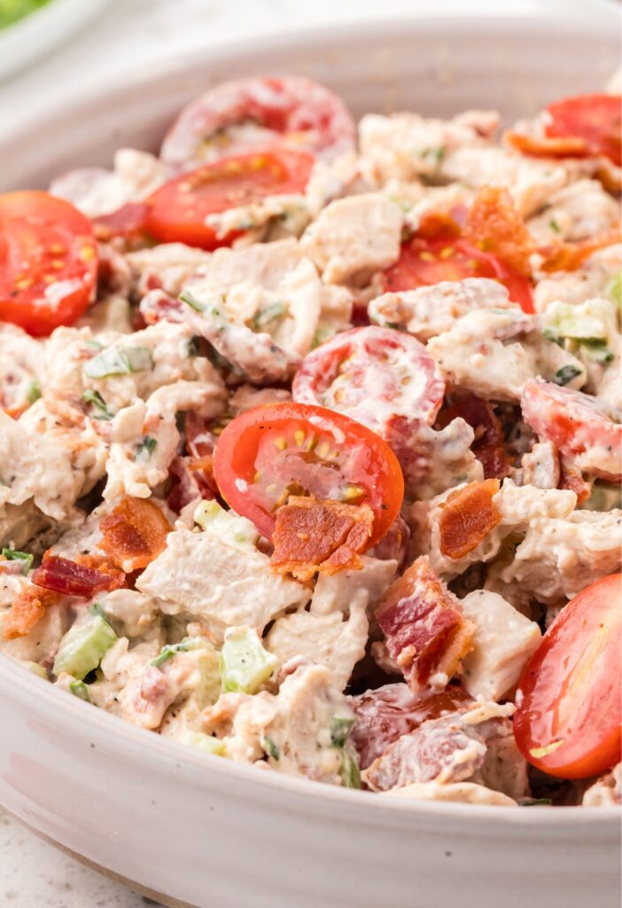 chicken salad inside a bowl with tomatoes, bacon, and chicken
