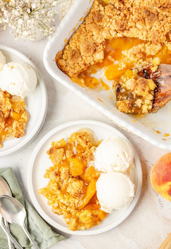 Baking dish of cake batter peach cobbler and a serving of it on a plate with ice cream