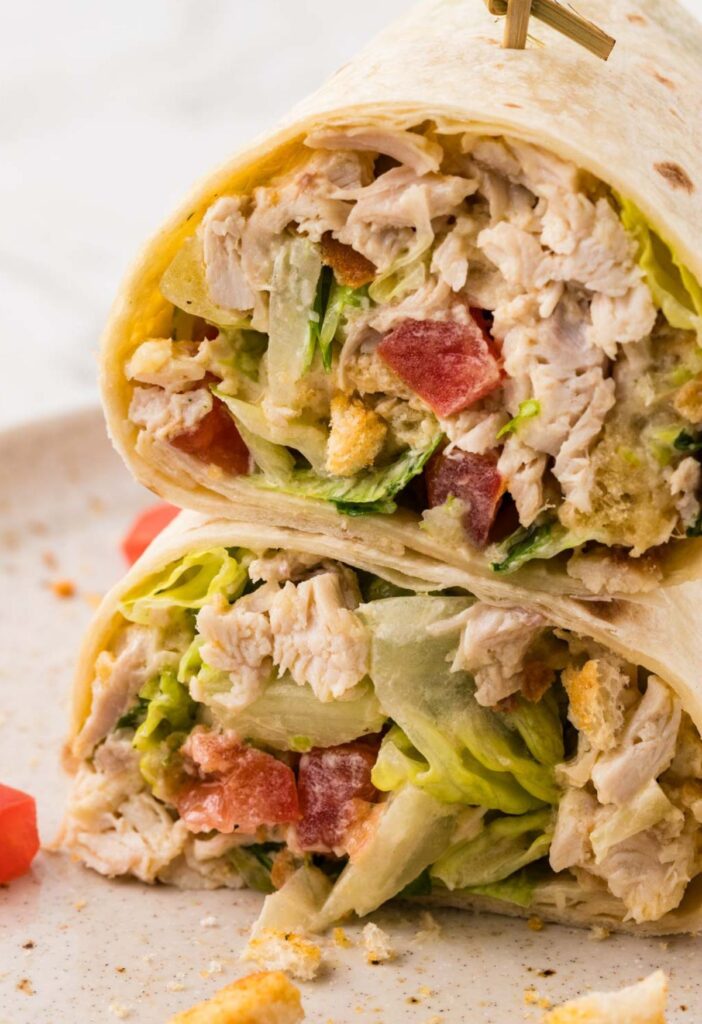 A chicken Caesar wrap cut in half and stacked on each other.