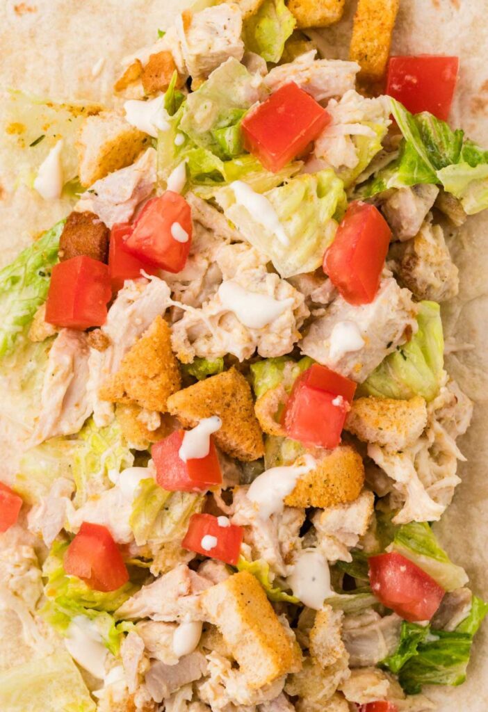 A large flour tortilla with the chicken wrap filling on it.