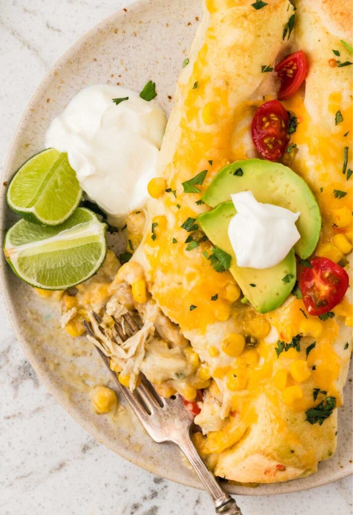 Two enchiladas with a fork taking a piece from them for eating.